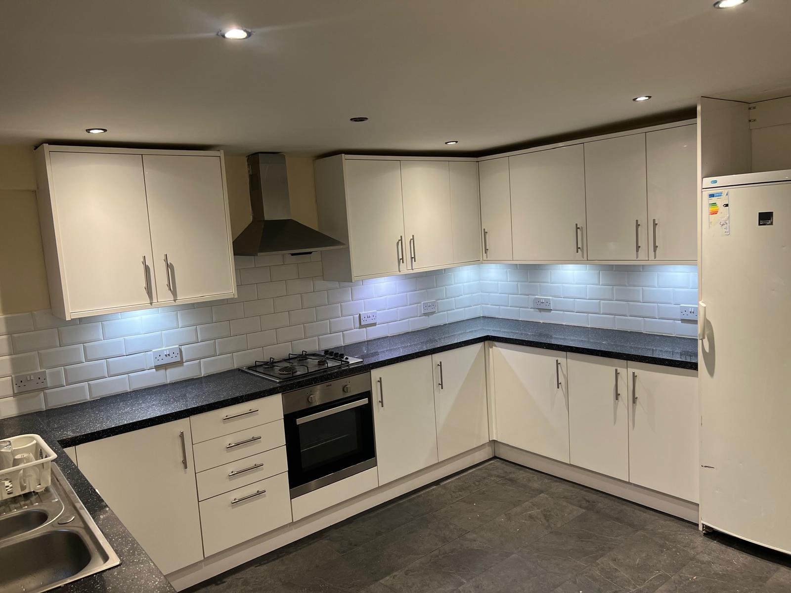 Completed kitchen with white cabinetry and tiled splashback